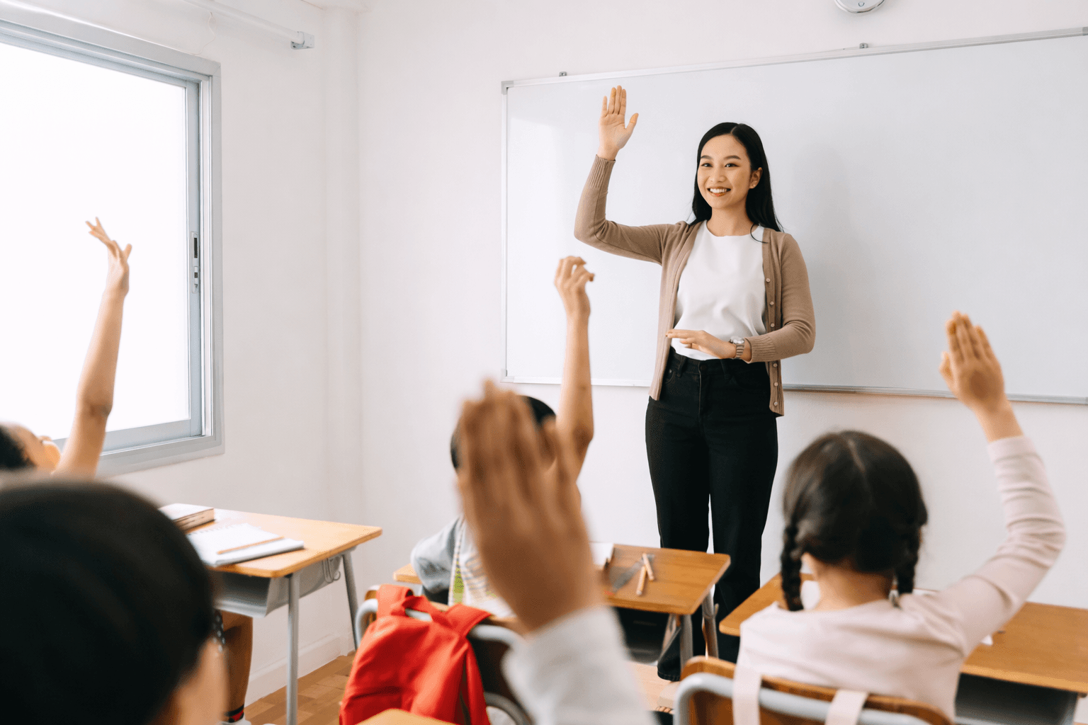 Teacher with students raising hands in a classroom